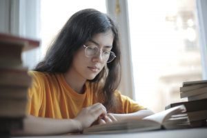 Woman studying while surrounded by books